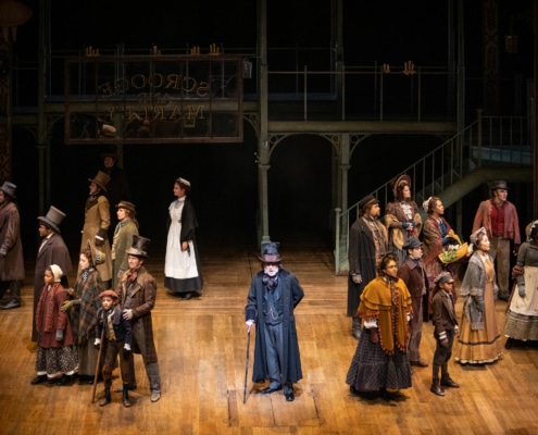 The cast of A Christmas Carol stands and sings onstage
