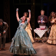 A woman raises her arms and shouts with joy in A Christmas Carol