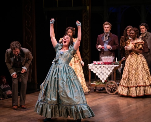 A woman raises her arms and shouts with joy in A Christmas Carol