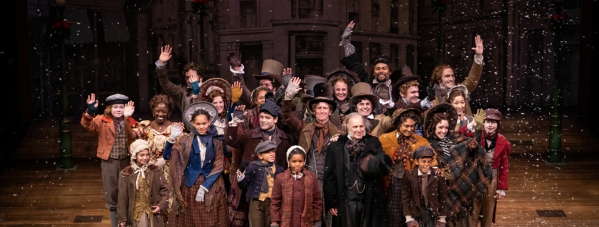 The cast of A Christmas Carol poses for a photo onstage