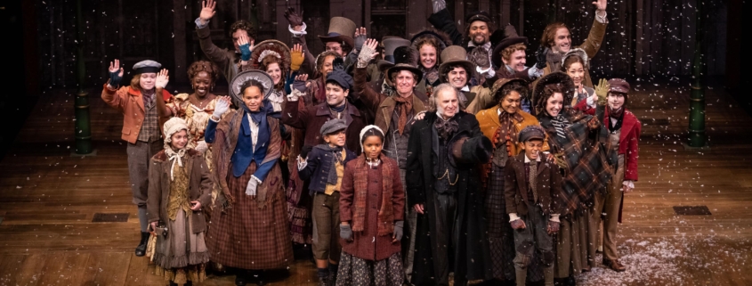 The cast of A Christmas Carol poses for a photo onstage