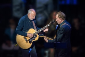 Des McAnuff and Pete Townshend play guitars together on stage, facing each other under concert lights.