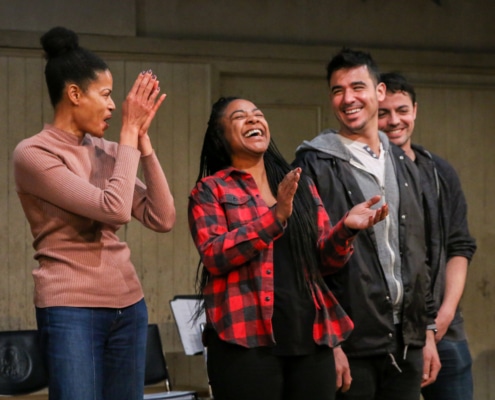 Four young adult actor stand in a row, smiling and clapping, at a DCPA Community Engagement event