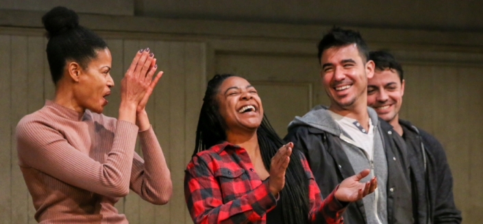 Four young adult actor stand in a row, smiling and clapping, at a DCPA Community Engagement event