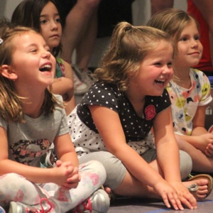 Four young girls sitting and laughing along as they watch something afar