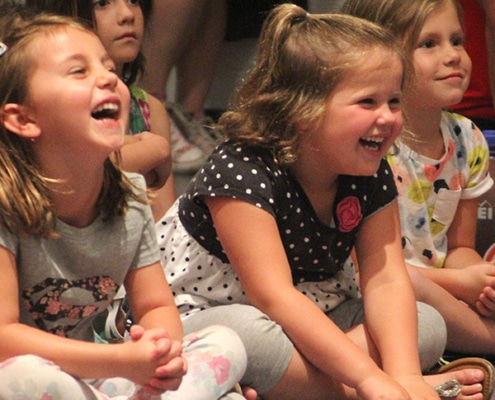 Four young girls sitting and laughing along as they watch something afar