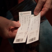 An individual holding a pair of tickets