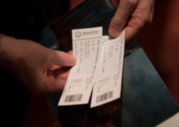 An individual holding a pair of tickets