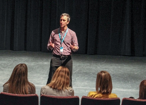 Timothy McCracken Teaching Artist standing on stage addressing an audience