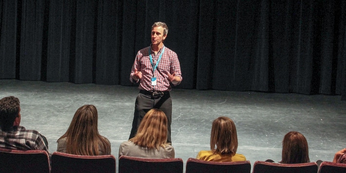 Timothy McCracken Teaching Artist standing on stage addressing an audience