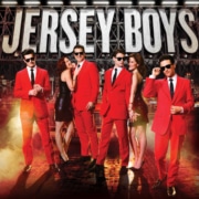 Jersey Boys. Four men in red suits and sunglasses accompanied by two doting women in black dresses. Fog effects and NYC skyline background