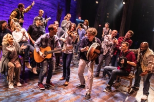 People sing and play instruments onstage in Come From Away