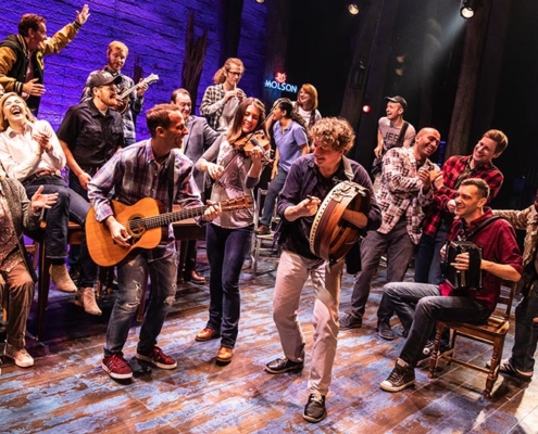 People sing and play instruments onstage in Come From Away