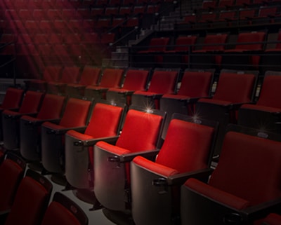 Empty red seats with a spotlight illuminating a single seat.