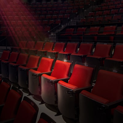 Empty red seats with a spotlight illuminating a single seat.