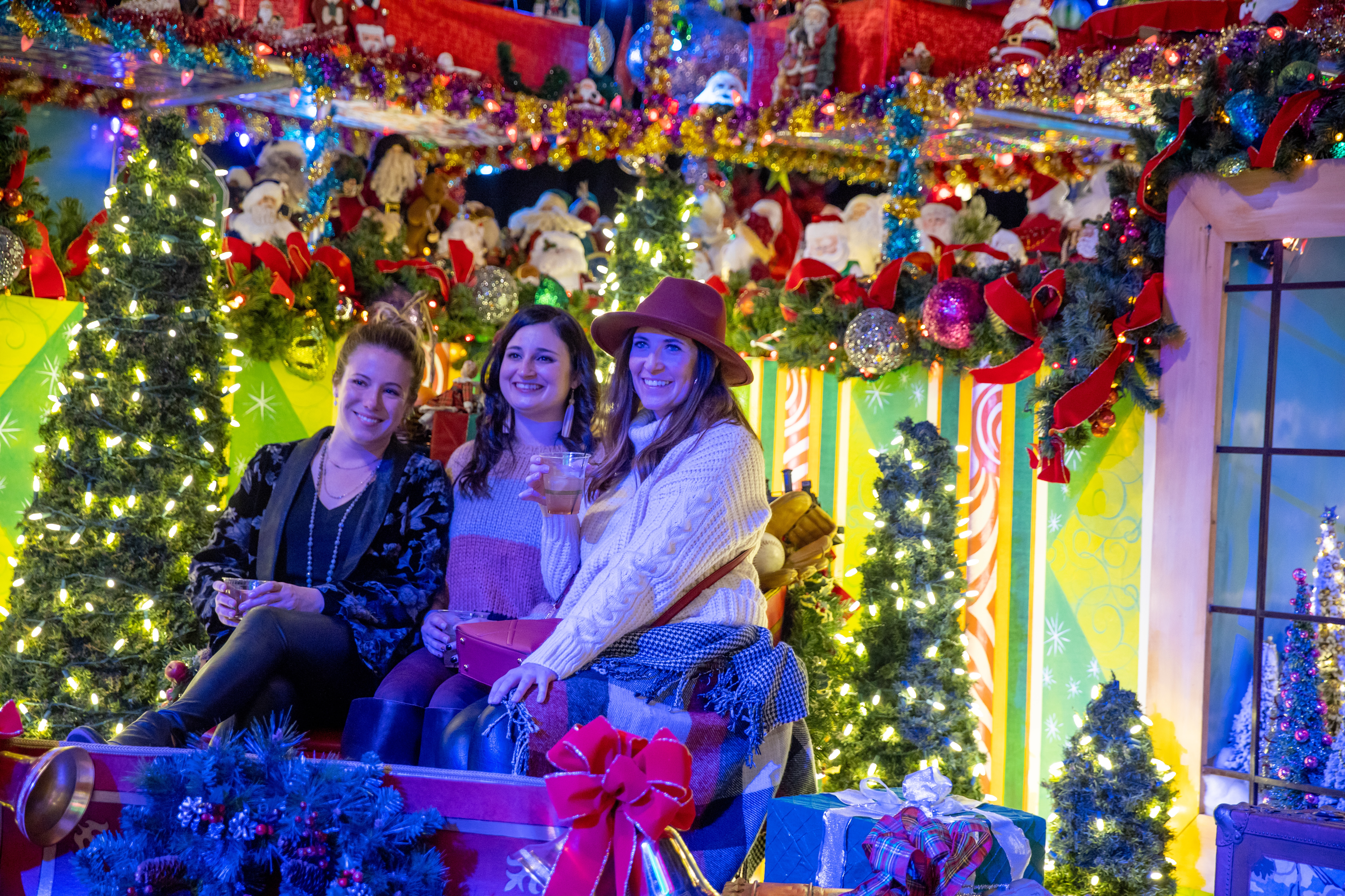 Three women pose while sitting in a sleigh at Camp Christmas