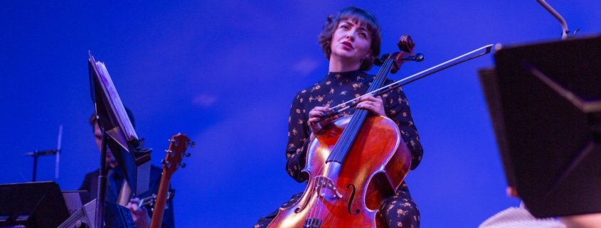 Singer playing cello on stage.