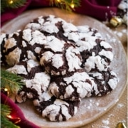 Chocolate crinkle cookies, garnished with powdered sugar, on a plate surrounded by Christmas decorations