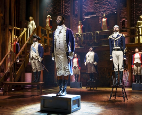 Cast of Hamilton Broadway National Tour stands on props onstage singing