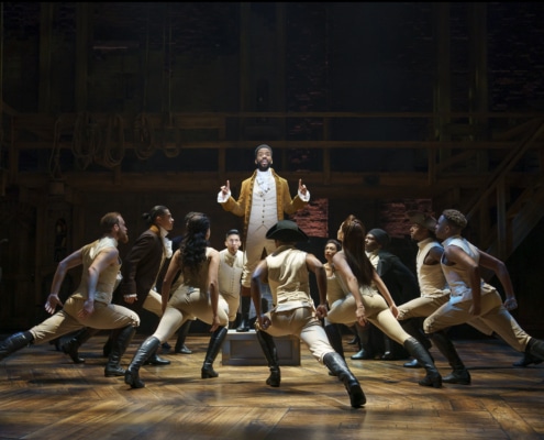 Alexander Hamilton stands on a box surrounded by dancers onstage in Hamilton Broadway National Tour