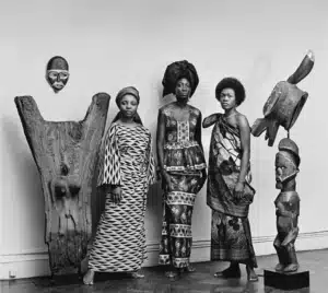 black models stand with African sculptures wearing African clothing in the 70s