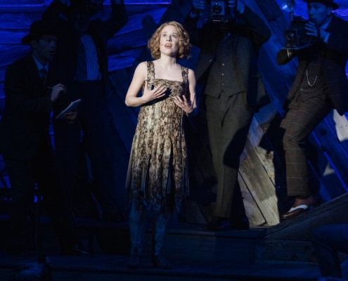 Alyse Alan Louis, as Kate, sings in the spotlight while wearing a rattlesnake skin flapper dress costume