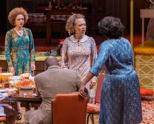 A group of actors argue onstage around a dinner table in In the Upper Room