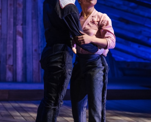 Isaac Huerta and Jada Simone Clark embrace and smile as they look towards the audience at a Denver Center production of Rattlesnake Kate