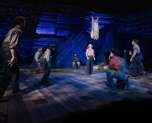 The cast of Rattlesnake Kate on stage with Alyse Alan Louis, portraying Kate, at center stage. All eyes are on the rattlesnake skin flapper suspended in mid-air.