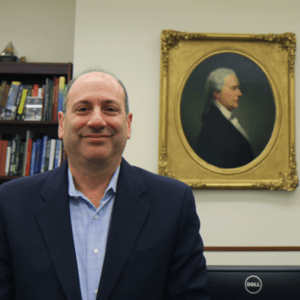 President of the Museum of American Finance, David Cowen, stands in front of a portrait of Alexander Hamilton