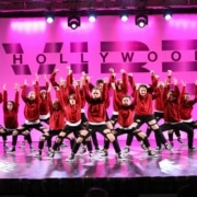 a group of dancers pose onstage in front of a hot pink background