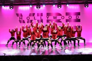 a group of dancers pose onstage in front of a hot pink background