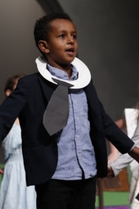 Child actor stands onstage in costume