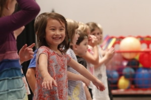 Children in acting class stand in a line, smiling