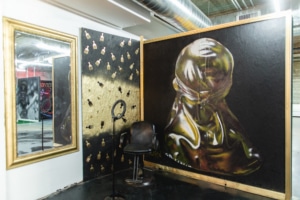 a barbershop chair sits in a corner surrounded by a black and gold mural at The Culture Museum