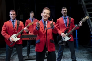 The Four Seasons face the camera and perform wearing red suits in Jersey Boys