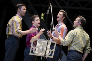 The Four Seasons stand at a microphone in a recording studio in Jersey Boys