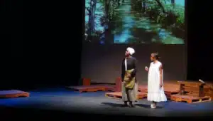 Actors onstage at the SOURCE theatre with a projected landscape behind them