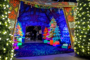 A blue room filled with neon Christmas trees at Camp Christmas