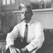 Black and white photo of a man in suit and tie smoking a cigar