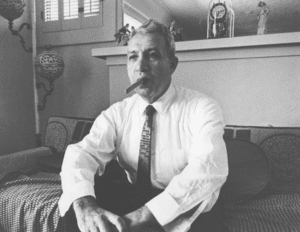 Black and white photo of a man in suit and tie smoking a cigar