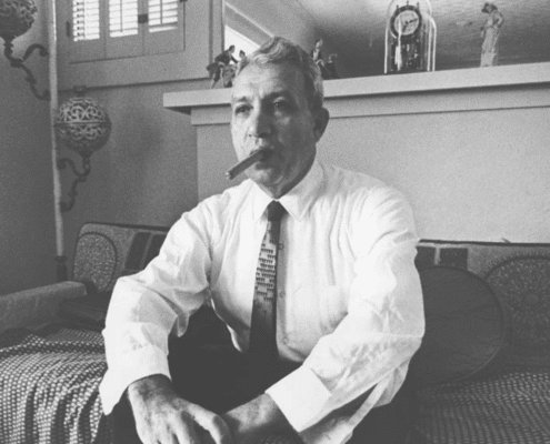 Black and white photo of a man in suit and tie smoking a cigar