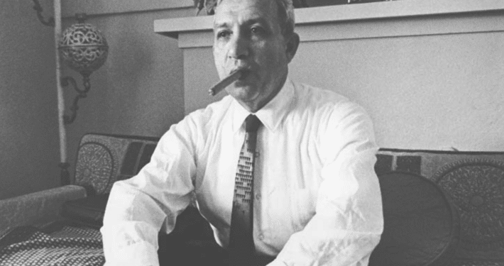 Black and white photo of a man in suit and tie smoking a cigar