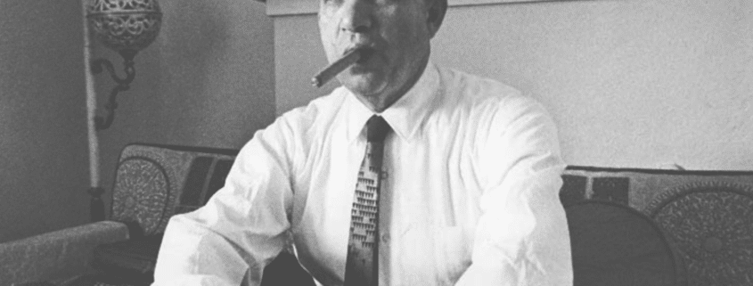 Black and white photo of a man in suit and tie smoking a cigar