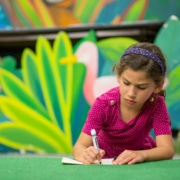 A young student in a DCPA Dramatic Learning workshop lays on the floor with a piece of paper