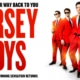 Promotional graphic for Jersey Boys featuring four performers in matching bright red suits and black ties against a white background. Large red text displays the show's title, while smaller text above and below notes the return of the Tony Award-winning musical. A gold emblem in the corner highlights the 20th anniversary tour.