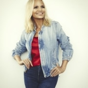 Actress and singer Kristin Chenoweth poses in a casual outfit in front of a white backdrop