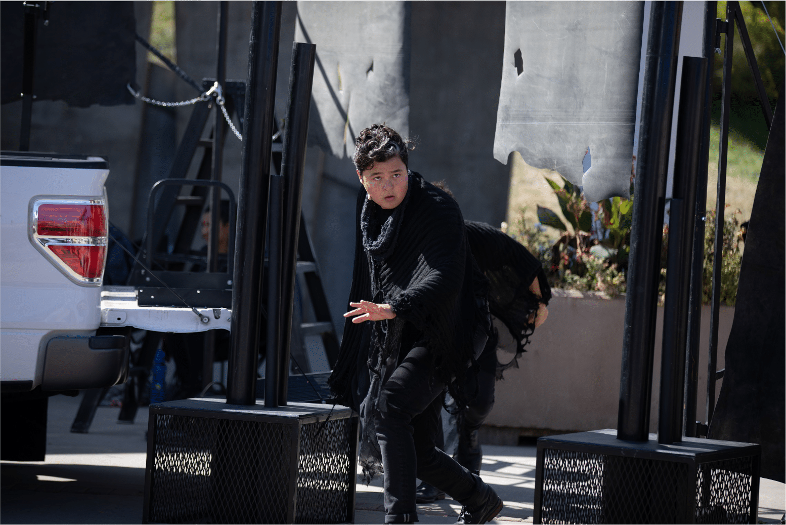 Actor dressed in black tatters sneakily creeps onto parking lot stage while looking at the audience