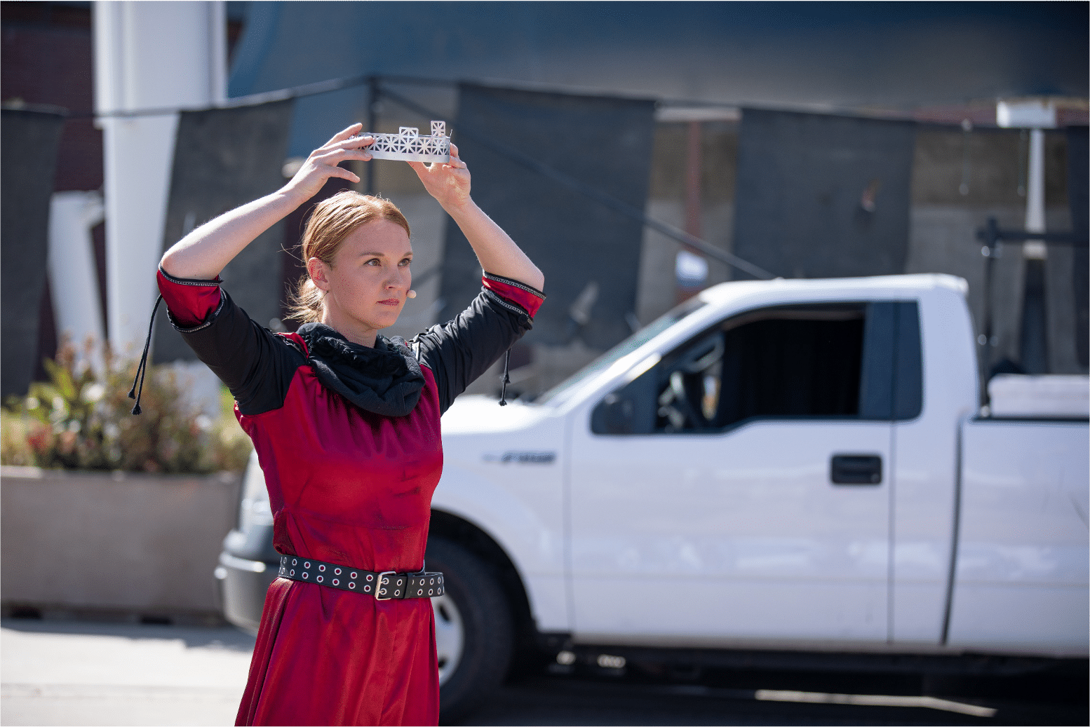 Actress in red holds a silver crown elegantly and powerfully above her own head