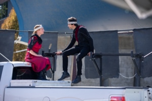 Actors sit in the bed of a pickup truck during a performance of Macbeth for Shakespeare in the Parking Lot